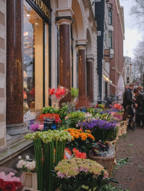 A vibrant display of fresh flowers arranged outside a florist shop on Old Brompton Road, featuring a diverse selection of colourful blooms including orange marigolds, purple tulips, pink roses, white